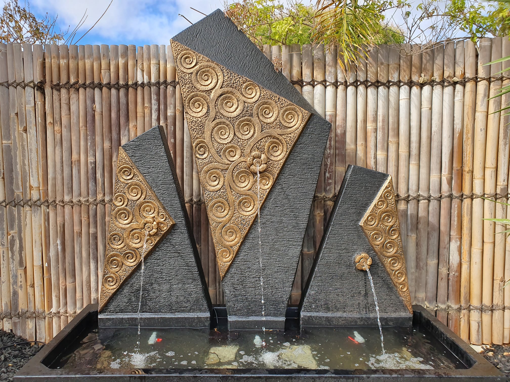 Water feature wall with angular panels and carved scrolled pattern.
