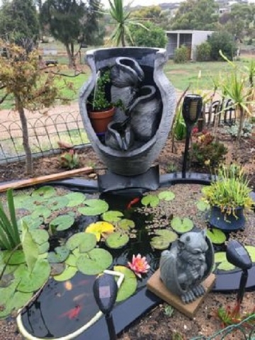 This cave pot water feature has been made to flow into this fish and lily pond.