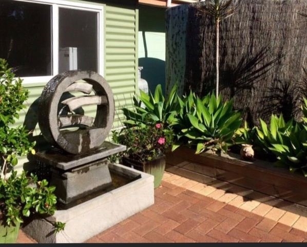 Water wheel water feature surrounded by potted plants