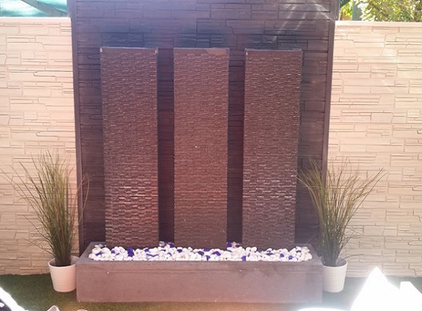Three panels of textured concrete in a base forming a large wall water feature