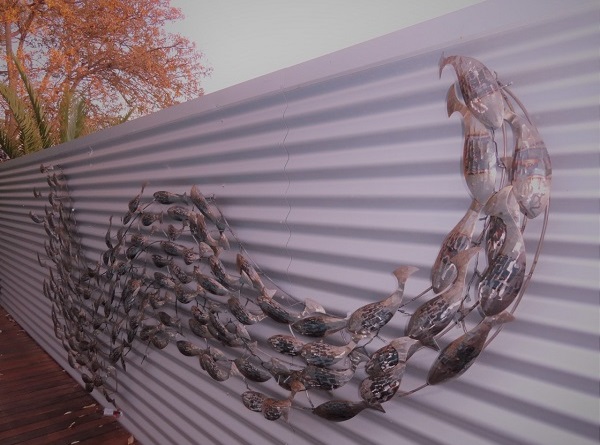A 3.5 meter school of metal fish on corrugated iron fence.